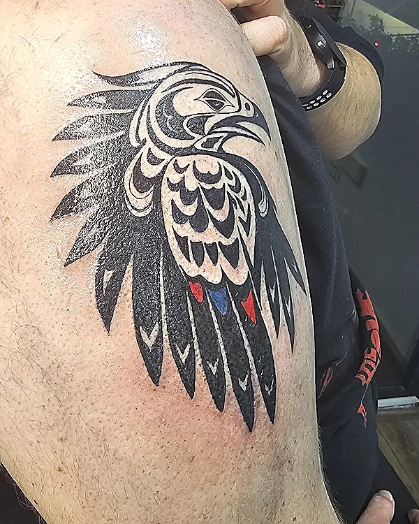 Ave de estilo gráfico en negro sólido con toques rojo y azul, en el hombro