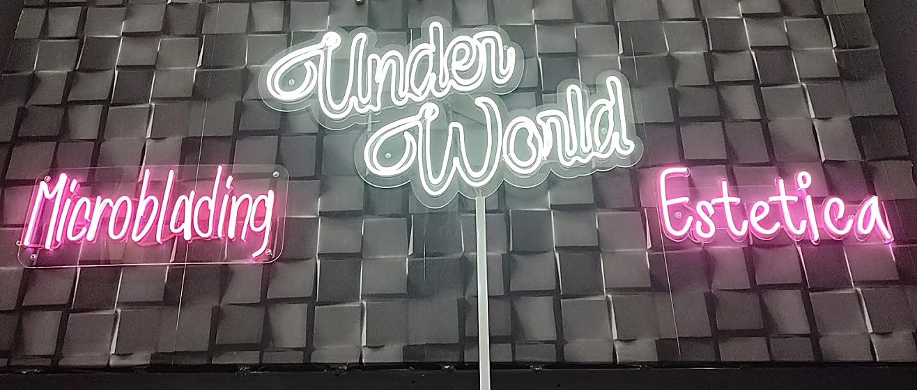 El muro de cubos del estudio con el neón blanco Under World al centro y dos neones rosa a los lados