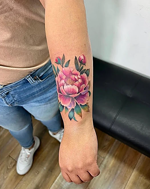Peonía rosa con hojas verdes a color en el antebrazo